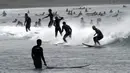 Orang-orang berselancar di pantai Katase-kaigan yang berangin, Fujisawa, Prefektur Kanagawa, selatan Tokyo, Jepang, Kamis (24/9/2020). Badai Tropis Dolphin bergerak di sepanjang pantai Pasifik Jepang. (AP Photo/Eugene Hoshiko)