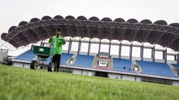 Pekerja sedang melakukan pemupukan rumput di Stadion Indomilk Arena, Tangerang pada Rabu (25/08/2021) sore WIB. Hal tersebut merupakan salah satu bentuk perawatan dan persiapan stadion untuk menyambut kompetisi BRI Liga 1 yang akan segera bergulir. (Foto: Bola.com/Bagaskara Lazuardi)