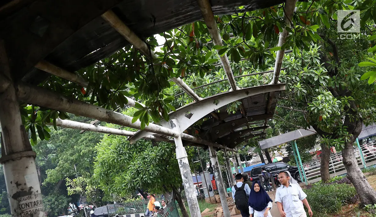 Warga melintasi jalur khusus pejalan kaki di kawasan Kampung Rambutan, Jakarta, Selasa (19/2). Atap rusak yang juga tidak dilengkapi dengan lampu penerangan mengganggu kenyamanan pejalan kaki. (Liputan6.com/Immanuel Antonius)