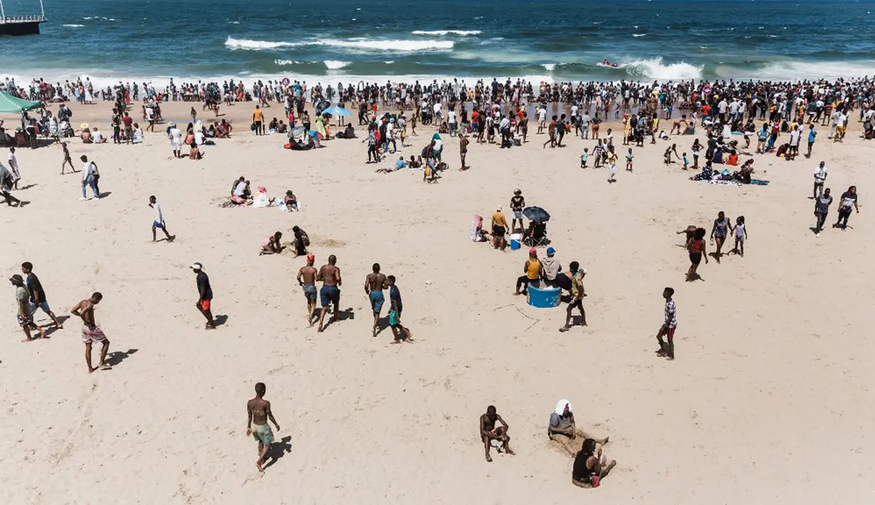 Ribuan wisatawan bersuka ria saat perayaan Tahun Baru di North Beach, Durban, Afrika Selatan, 1 Januari 2022. Menurut polisi Afrika Selatan, hampir 50 ribu orang diperkirakan akan menghabiskan hari di pantai. (Rajesh JANTILAL/AFP)