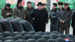 Pemimpin Korut, Kim Jong-un berbincang dengan para pekerja di pabrik ban lokal di di Chagang, Korut (3/11). Kim Jong-un tampil dengan mengenakan jas dan topi hitam saat mengunjungi pabrik ban tersebut. (KCNA/via AP)