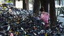 Seorang wanita berjalan melintasi sepeda-sepeda yang diparkir di atas trotoar di Beijing, China (21/7/2020). Seperti diketahui Beijing telah menerapkan bike sharing yang sudah tersedia di trotoar-trotoar Kota Beijing. (AFP Photo/Greg Baker)