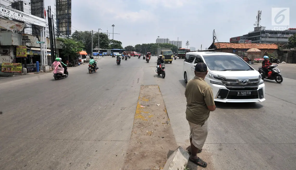 Seorang warga saat membantu pengendara melintasi persimpangan Terminal Pulo Gadung, Jakarta, Rabu (5/9). Kecelakaan lalu lintas di persimpangan ini sering terjadi pada malam hari. (Merdeka.com/Iqbal Nugroho)