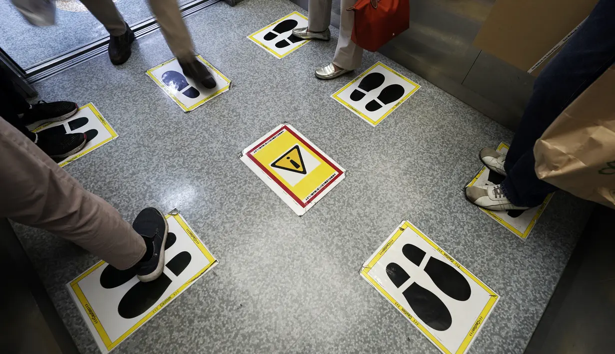 Stiker jarak sosial terlihat di lift di gedung perbelanjaan di Tokyo, Senin (28/9/2020). Ibukota Jepang mengonfirmasi lebih dari 70 kasus virus corona pada hari Senin. (AP Photo / Eugene Hoshiko)