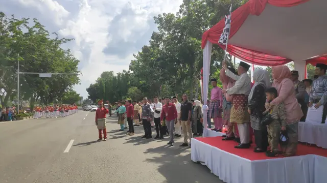 Penjabat Bupati Kampar Kamsol mengangkat bendera sebagai tanda dimulainya pawai atau karnaval Bagholek Godang  (Liputan6.com / M. Syukur).