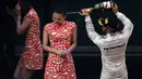 Lewis Hamilton menyemprotkan sampanye ke arah gadis podium.