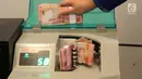 Petugas tengah menghitung uang rupiah menggunakan mesin di Bank BUMN, Jakarta, Selasa (17/4). Rupiah siang ini melemah dibandingkan tadi pukul 09.00 WIB di level Rp 13.771 per dolar AS. (Liputan6.com/Angga Yuniar)