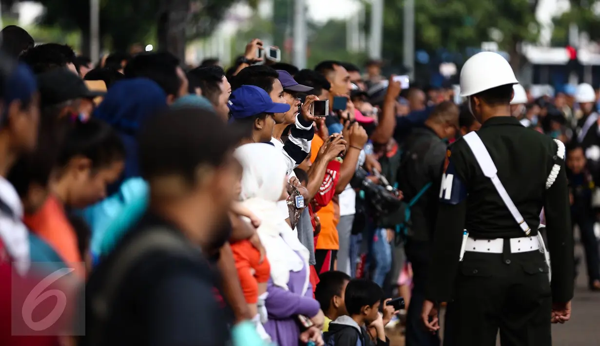 Antusias warga melihat anggota Paspampres melakukan prosesi pergantian jaga Istana Kepresiden di depan Istana Merdeka, Minggu (28/8). Ini merupakan pelaksanaan seremoni pergantian pasukan jaga istana untuk yang kedua kalinya (Liputan6.com/Faizal Fanani)