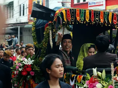 Presiden Joko Widodo bersama Ibu Negara Iriana saat membagikan kaus di atas kereta kencana saat kirab resepsi pernikahan Kahiyang Ayu-Bobby Nasution di Kota Medan, Sumatera Utara, Minggu (26/11). (Liputan6.com/Johan Tallo)