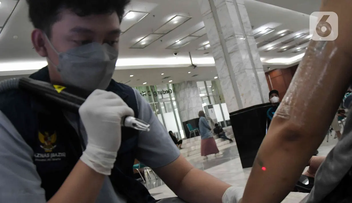 Petugas (kanan) menghapus tato pada lengan seorang warga saat program hapus tato gratis di Kantor Wali Kota Jakarta Timur, Selasa (4/4/2023). (Liputan6.com/Herman Zakharia)