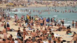 Pengunjung berjemur di pantai Bondi ketika pantai Bondi ketika suhu udara melonjak di Sydney (21/12/2019). Pemerintah negara bagian tersebut juga sudah mendeklarasikan status darurat karena situasi saat ini membahayakan warga dan wisatawan. (AFP/Farooq Khan)