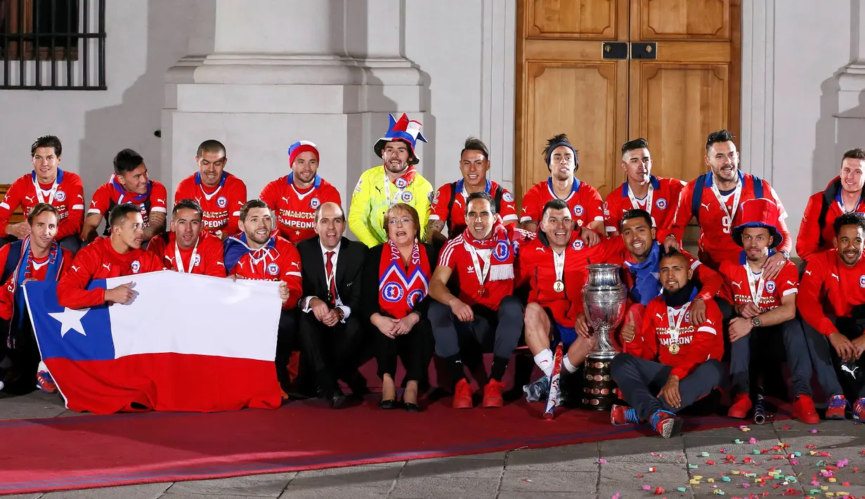 Presiden Chile Michelle Bachelet dan pemain Chile berpose dengan trofi Copa America di istana kepresidenan La Moneda, Chili (4/7/2015). Chili menang lewat adu penalti atas Argentina dengan skor 4-1. (REUTERS/Rodrigo Garrido)