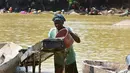 Seorang penembang emas wanita menyaring kerikil dan memisahkan bintik-bintik emas dari lumpur di sungai Pampana di dekat Mekeni, sebelah utara Sierra Leone (5/3). (AFP Photo/Issouf Sanogo)