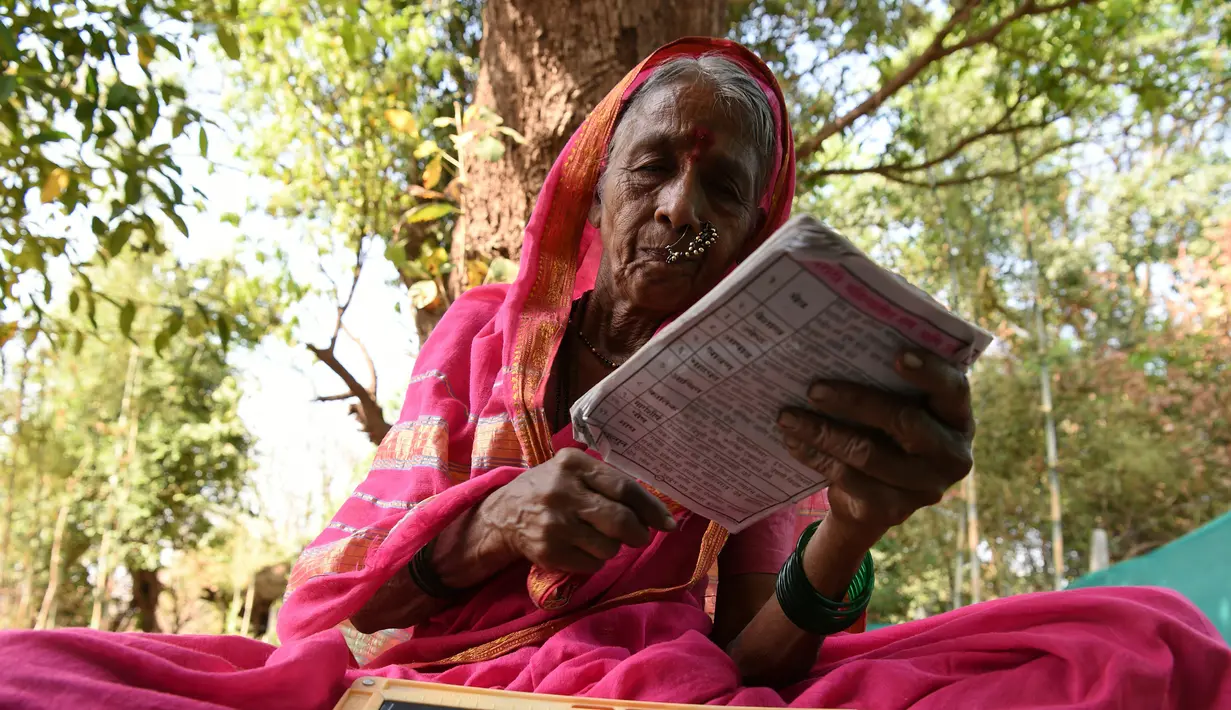 Nenek Sulochona Kedar (68) membaca buku selama mengikuti kegiatan di Sekolah Aajibaichi Shaala, Desa Fangane, India, pada 1 Maret 2017. Sama seperti sekolah pada umumnya, Sekolah ini memiliki aturan dalam berpakaian. (AFP Photo / Indranil Mukherjee)