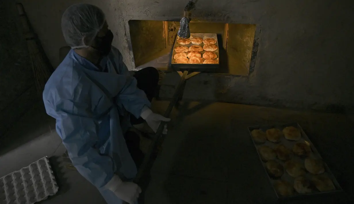 Pekerja mengeluarkan kue yang dipanggang dari oven di sebuah toko roti di Srinagar, India, Senin (18/5/2020). Toko roti tersebut melayani pengiriman untuk umat muslim yang merayakan Lebaran. (Tauseef MUSTAFA/AFP)