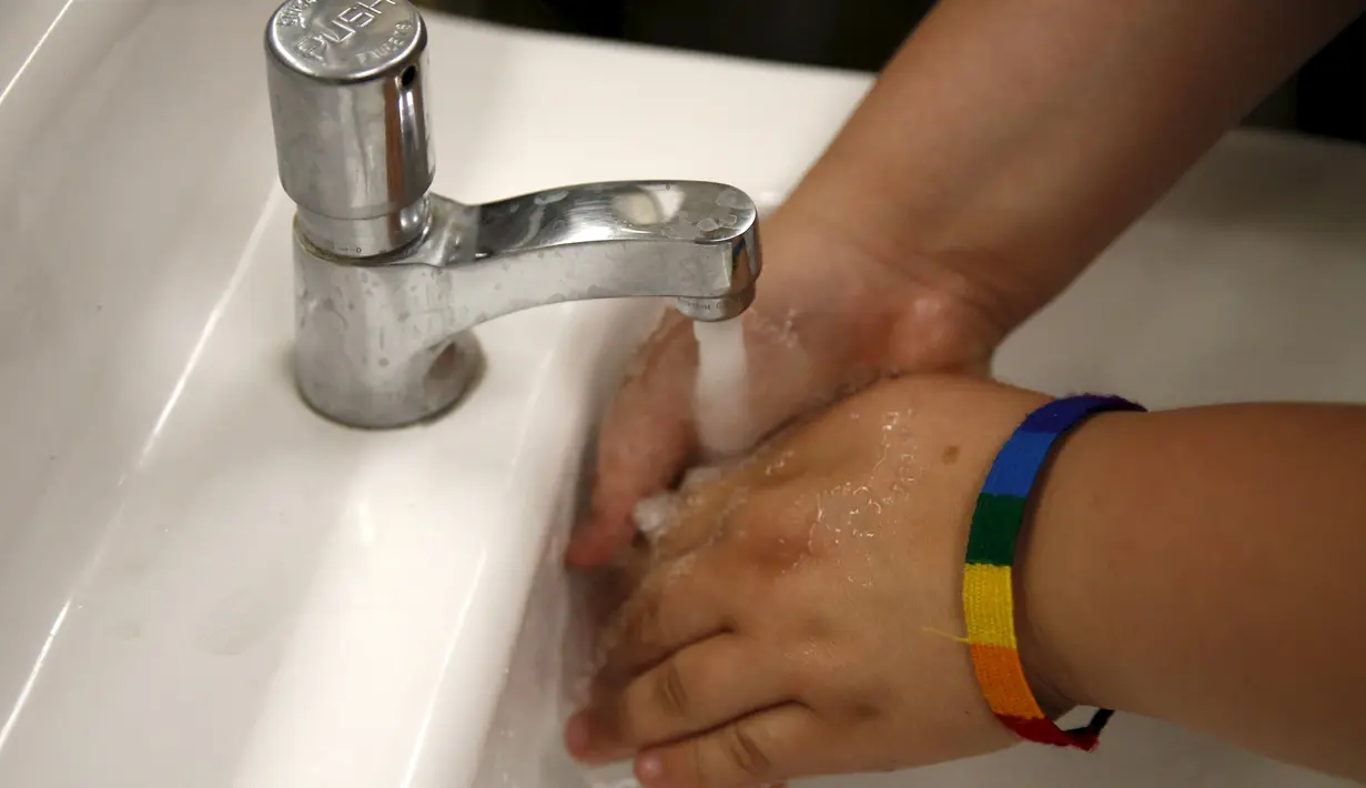 Seorang siswa mencuci tangan di toilet netral gender pertama di Santee High School, Los Angeles, California, AS, Senin (18/4). Toilet disediakan sebagai langkah mendukung dan menampung siswa transgender. (REUTERS/Lucy Nicholson)