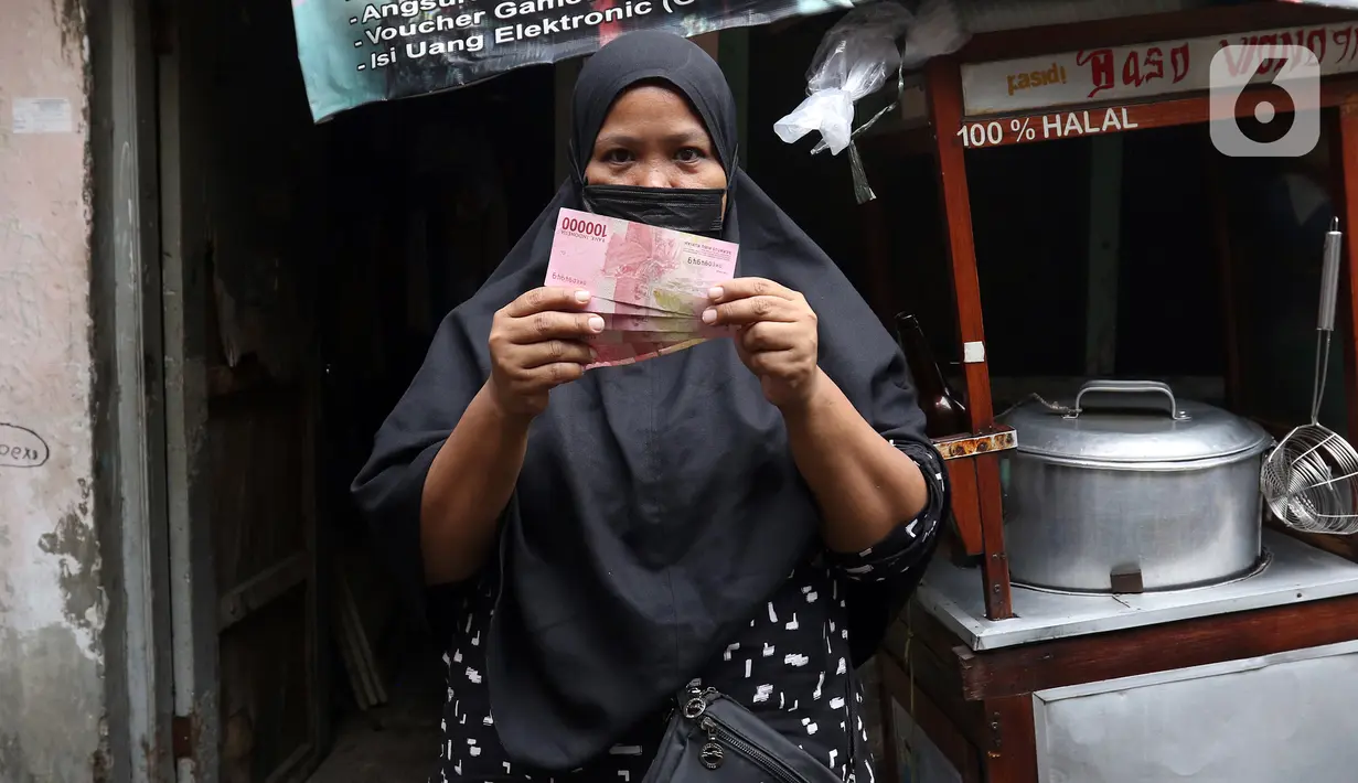 Warga menunjukkan Bantuan Sosial Tunai (BST) yang disalurkan petugas pos dari rumah ke rumah di kawasan Kebon Jahe, Jakarta Pusat, Rabu (21/7/2021). BST senilai Rp 600 ribu disalurkan untuk dua periode yakni bulan Mei-Juni. (Liputan6.com/Herman Zakharia)