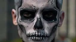 Seorang pria berpose dengan kostum dan dandanan menyerupai zombie dalam acara Zombie Walk di Sao Paulo, Brasil, Jumat (2/11). Ribuan orang beraksi sebagai Zombie untuk memeriahkan peringatan Hari Para Arwah yang diadakan sejak 2006. (Mauro PIMENTEL/AFP)
