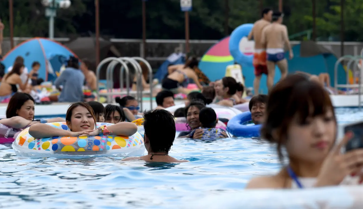 Pengunjung menghabiskan waktu di kolam renang di sebuah taman hiburan di Tokyo, Jepang (19/7). Badan Meteorologi Jepang mengumumkan Jepang tengah, termasuk Tokyo, telah menyelesaikan musim hujan 'Tsuyu'.  (AFP Photo/Toshifumi Kitamura)