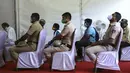 Polisi India menunggu bersama orang lain untuk menerima vaksin COVID-19 dosis ketiga di pusat vaksinasi di Bengaluru, India (10/1/2022). Penyebaran varian Omicron yang cepat telah memicu lonjakan kasus baru hingga delapan kali lipat sejak awal tahun. (AP Photo/Aijaz Rahi)