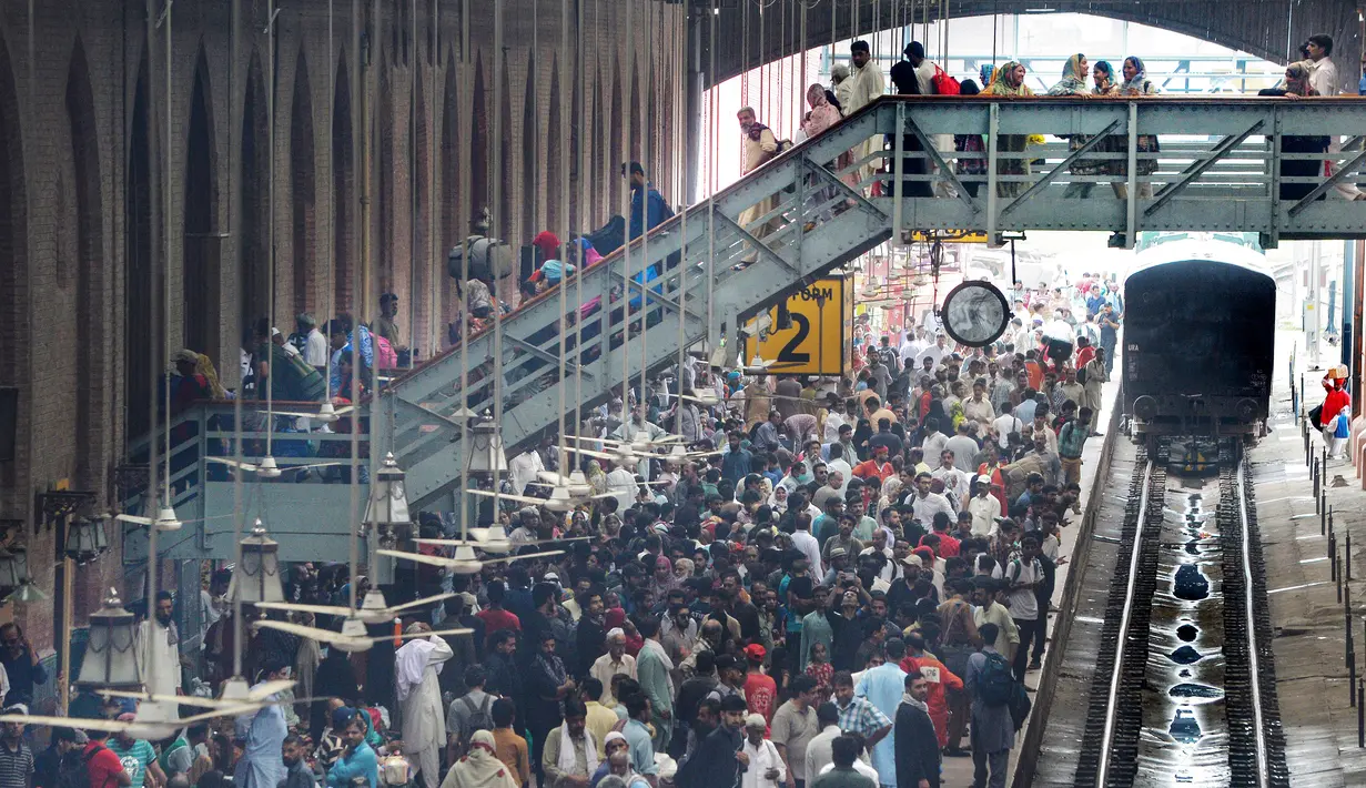 Para pelancong menunggu rangkaian kereta saat mudik menuju kampung halaman untuk merayakan Idul Adha di stasiun Lahore, Pakistan, Sabtu (10/8/2019). Umat Islam di seluruh dunia merayakan Idul Adha yang identik dengan tradisi berkurban. (Photo by ARIF ALI / AFP)