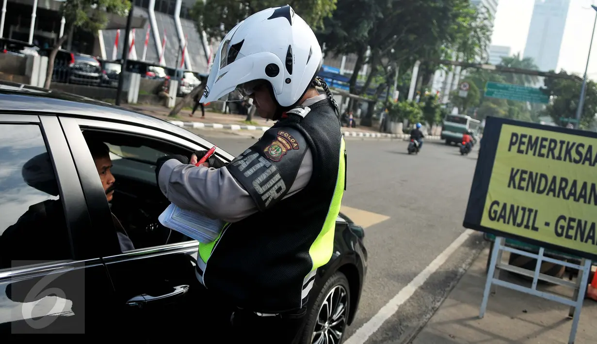 Petugas menilang pengendara mobil berpelat genap yang melintas pada tanggal ganjil di Bundaran Senayan, Jakarta, Rabu (31/8). Sejak kemarin mulai diberlakukan sanksi kepada pengendara yang melanggar aturan ganjil-genap. (Liputan6.com/Gempur M Surya)