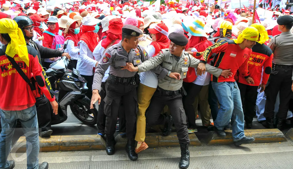 Personel kepolisian berusaha menahan para bidan desa yang berupaya menutup akses jalan saat demonstrasi di depan gedung Kemenkes, Jakarta, Rabu (4/5). Para bidan menuntut diangkat menjadi pegawai tetap tanpa syarat.  (Liputan6.com/Yoppy Renato)