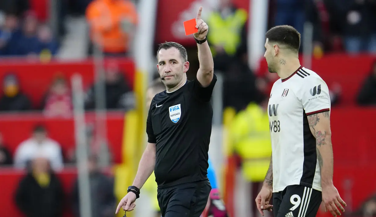 Pemain Fulham, Aleksandar Mitrovic (kanan), menatap wasit Chris Kavanagh yang memberikan kartu merah kepada Willian yang menghalau bola menggunakan tangannya untuk mencegah gawang timnya kebobolan dalam babak perempat final Piala FA 2022/2023 melawan Manchester United yang berlangsung di Old Trafford, Minggu (19/3/2023) malam WIB. (AP Photo/Jon Super)