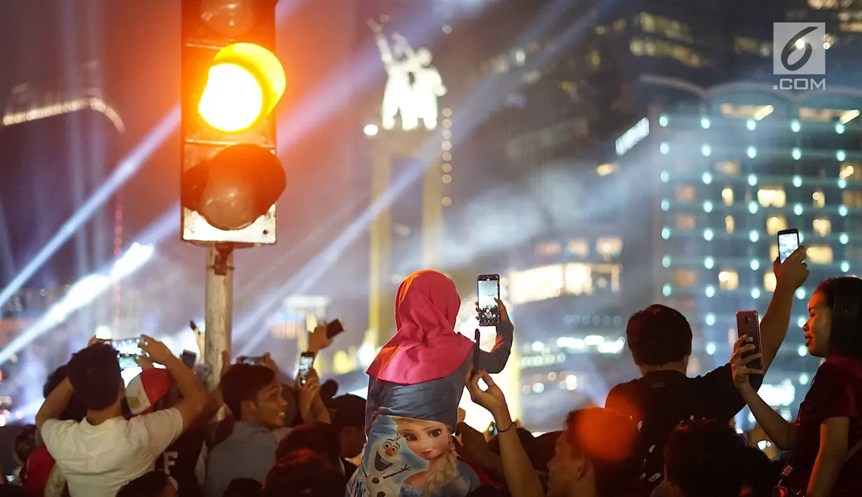Warga menyaksikan hiburan menggunakan telepon genggam pada malam puncak peringatan HUT DKI Jakarta ke-492 di Bundaran HI Jakarta, Sabtu, (22/6/2019). Peringatan HUT Jakarta yang dibuka Gubernur DKI Jakarta Anies Baswedan dikemas dalam konsep ekonomi kreatif dan seni. (Liputan6.com/Immanuel Antonius)