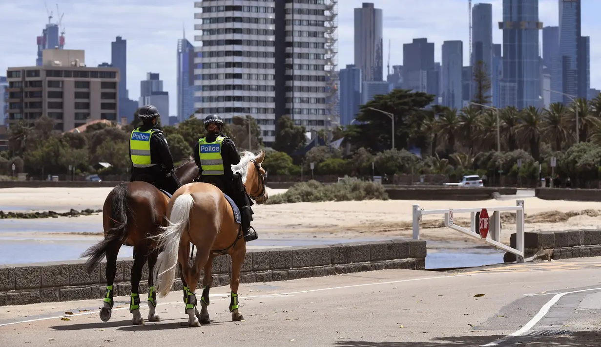 Polisi berpatroli dengan menunggang kuda di sepanjang St Kilda Esplanade di Melbourne (26/10/2020). Australia telah menghabiskan berbulan-bulan di bawah pembatasan yang berat setelah menjadi episentrum gelombang kedua negara itu. (AFP Photo/William West)