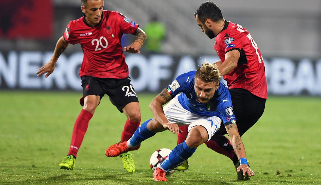 Striker Italia, Ciro Immobile, terjatuh saat berusaha melewati bek Albania, M‘rgim Mavraj, pada laga kualifikasi Piala Dunia 2018 di Stadion Loro Borici, Senin (9/20/2017). Italia menang 1-0 atas Albania. (AFP/Dimitar Dilkoff)