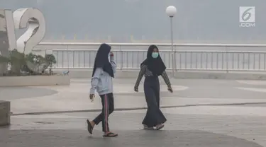 Dua wanita mengenakan masker saat mengunjungi alun-alun Kabupaten Siak, Riau, Kamis (12/9/2019). Asap pekat kebakaran lahan gambut tersebut selain mengganggu kesehatan serta mencemari udara sehingga kualitasnya turun ke status tidak sehat. (Liputan6.com/Faizal Fanani)