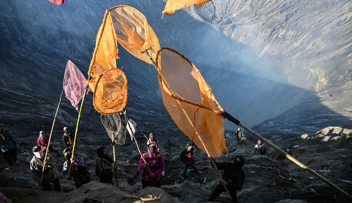 Warga desa menangkap persembahan yang dilemparkan oleh umat Hindu dari komunitas Tengger ke kawah Gunung Bromo selama festival Yadnya Kasada di dekat Probolinggo, Jawa Timur, Senin 1 Juni 2026. (JUNI KRISWANTO/AFP)