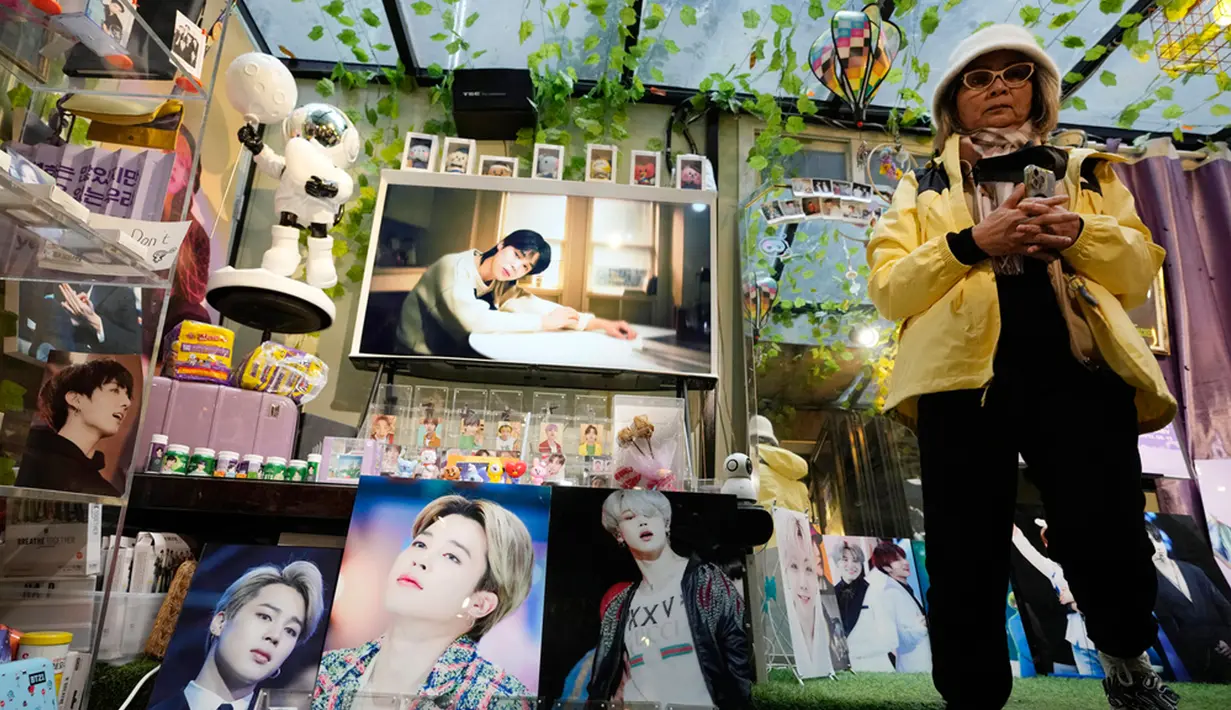 Seorang wanita melewati gambar anggota band K-Pop Korea Selatan BTS di sebuah kafe di Seoul, Korea Selatan, Senin (11/12/2023). (AP Photo/Ahn Young-joon)