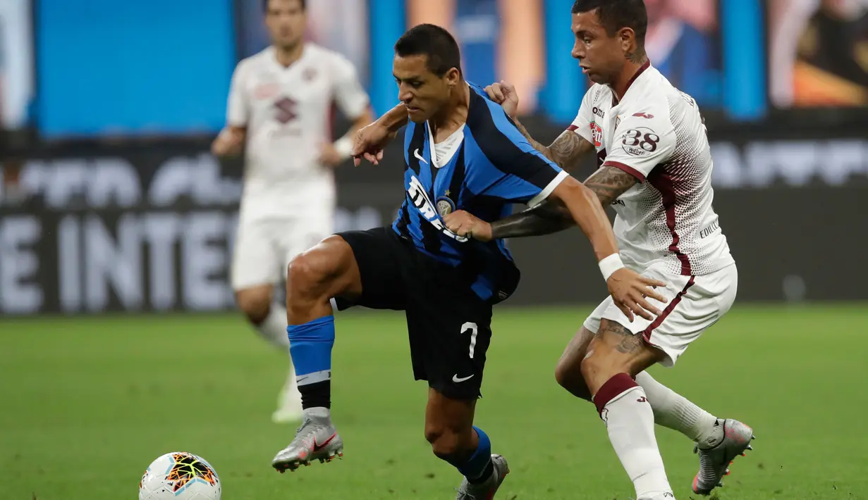Penyerang Inter Milan, Alexis Sanchez  menggiring bola dari kawalan pemain Torino, Armando Izzo pada pertandingan lanjutan Liga Serie A Italia di stadion San Siro di Milan, Italia (13/7/2020). Inter Milan menang telak 3-1 atas Torino. (AP Photo/Luca Bruno)