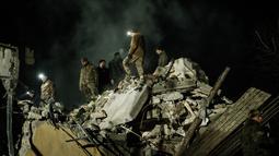 Tim penyelamat memindahkan puing-puing untuk mencari korban selamat di gedung apartemen yang hancur terkena roket pada malam hari di pusat kota Kramatorsk, Ukraina timur, pada Rabu (1/2/2023). Seperti dilansir AFP, serangan rudal Rusia itu dilaporkan terjadi pada Rabu malam, sekitar pukul 21.45 waktu setempat. (Yasuyoshi CHIBA / AFP)