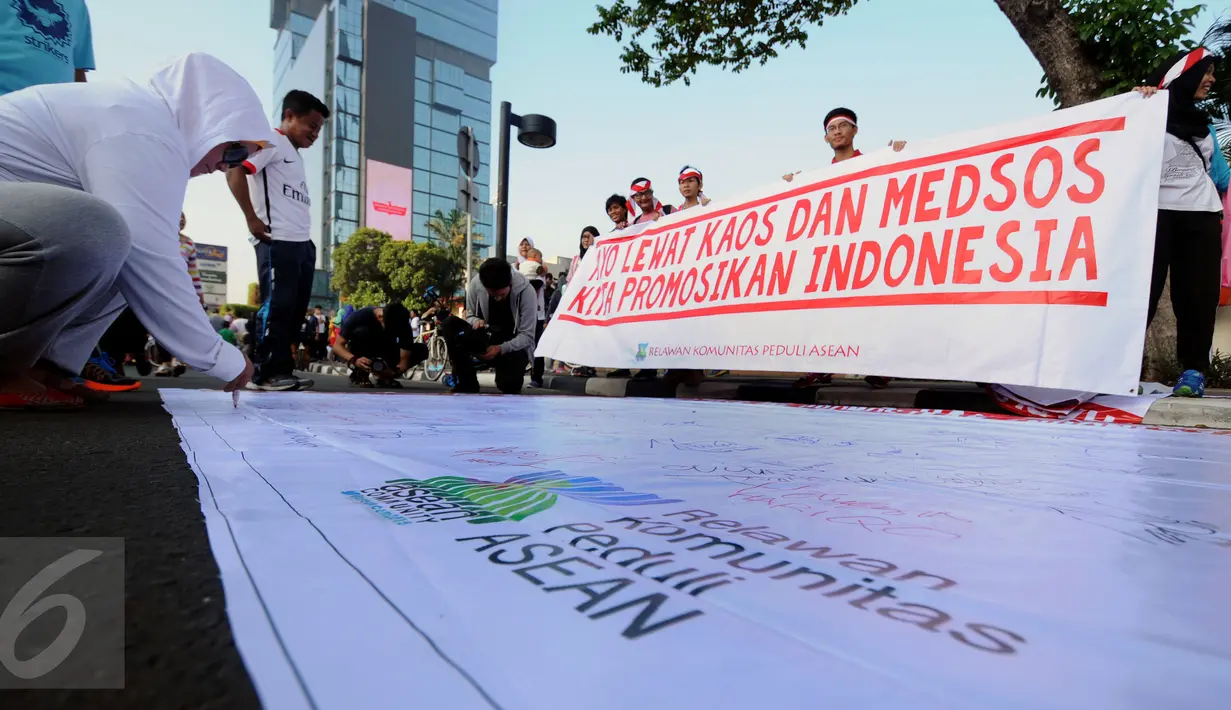 Warga menandatangani spanduk Relawan Komunitas Peduli ASEAN di Jakarta, Minggu (13/3/2016). Relawan ini mengajak masyarakat menggunakan kaos bergambar tentang ke-Indonesia-an dan memposting ke seluruh media sosial. (Liputan6.com/Helmi Fithriansyah)