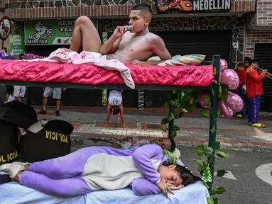 Pria dan wanita tidur di atas ranjang saat merayakan Hari Malas Sedunia di Itagui, dekat Medellin, Kolombia, Minggu (18/8/2019). Warga Kolombia membawa tempat tidur mereka ke jalanan untuk memperingati Hari Malas Sedunia. (JOAQUIN SARMIENTO/AFP)