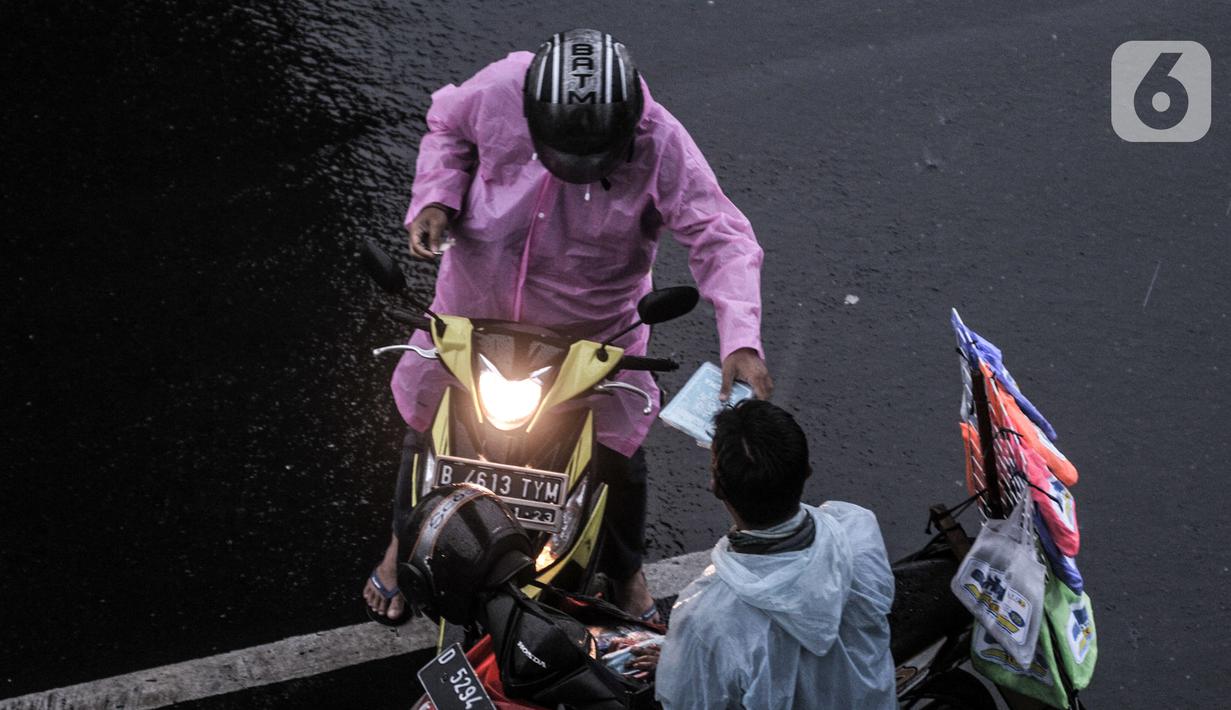 Pengendara motor membeli jas ponco saat hujan mengguyur Jakarta, Senin (26/10/2020). BPBD DKI Jakarta mengeluarkan peringatan dini cuaca berupa potensi terjadinya hujan lebat disertai petir dan angin kencang dampak dari siklon tropis Molave hingga 27 Oktober 2020. (merdeka.com/Iqbal S. Nugroho)