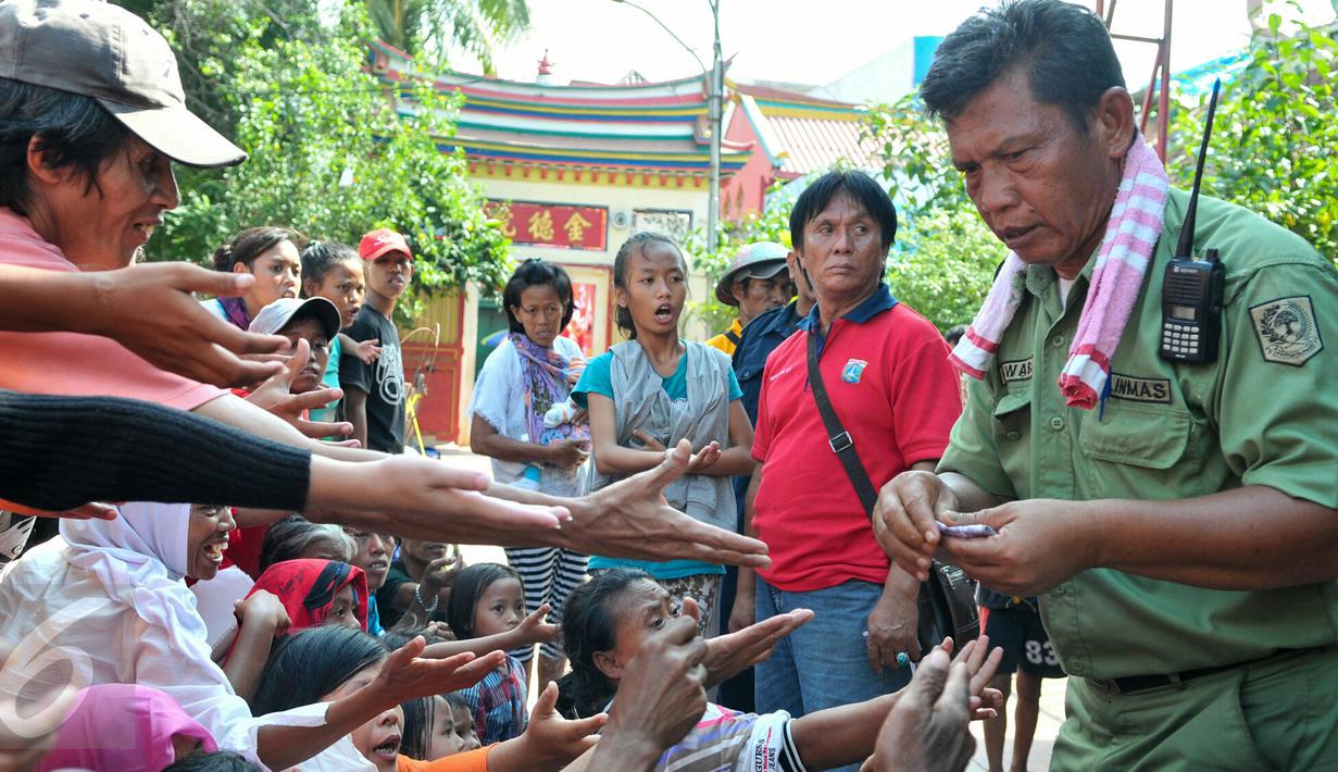 Petugas Vihara Dharma Bakti membagikan angpao dari umat Tionghoa yang datang untuk sembahyang jelang perayaan Imlek, Jakarta, (7/2/2016). Jelang Imlek, ratusan pengemis penuhi Vihara Dharma Bhakti untuk mendapatkan angpao. (Liputan6.com/Yoppy Renato)