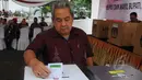 Seorang petugas memasukan kertas suara ke dalam kotak pada simulasi pemungutan dan penghitungan suara Pemilihan Gubernur, Bupati, serta Walikota di TPS Halaman Gedung KPU RI, Jakarta Pusat, Selasa (7/4/2015). (Liputan6.com/Herman Zakharia)
