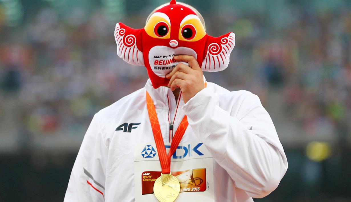 Atlet Polandia, Piotr Malachowski, menutup wajahnya dengan maskot Kejuaraan Dunia Atletik 2015 setelah meraih emas lempar lembing putra di Stadion Nasional, Beijing, Tiongkok. Minggu (30/8/2015). (Reuters/Damir Sagolj)