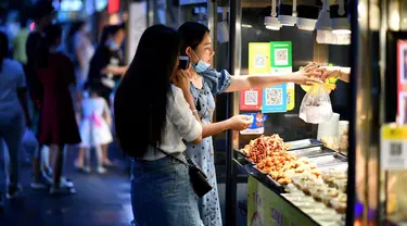 Dua wanita membeli makanan di pedagang kaki lima di Haikou, ibu kota Provinsi Hainan, China selatan (26/3/2020). Provinsi Kepulauan Hainan di China selatan pada Selasa (24/3) mencatatkan penurunan jumlah kasus penyakit coronavirus baru (COVID-19) yang ada menjadi nol. (Xinhua/Guo Cheng)