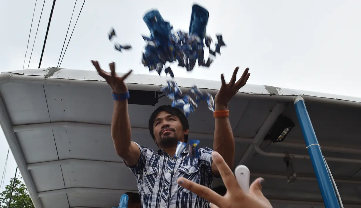  Mantan petinju Filipina, Manny Pacquiao melempar baju dan permen untuk pendukung selama kampanye di kota Calamba, Provinsi Laguna, selatan Manila (28/4). Manny Pacquiao akan ikut  pemilihan menjadi senat Filipina. (AFP PHOTO/TED aljibe)