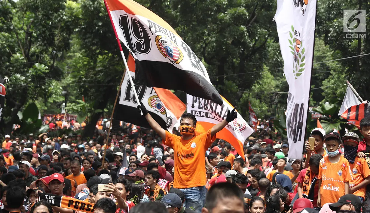 Jakmania mengibarkan bendera Persija saat penyerahan piala Liga I di depan Balai Kota, Jakarta, Sabtu (15/12). Persija kembali meraih juara Liga Indonesia setelah 17 tahun. (Liputan6.com/Herman Zakharia)