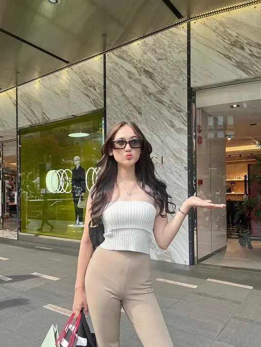 Laura Moane tampil chic dibalut knitted tube top berwarna putih, dipadunya dengan celana panjang berwarna cokelat. Gayanya semakin manis dengan sunglasses dan mini bag berwarna hitam. [Foto: Instagram/its_lauramoane2]