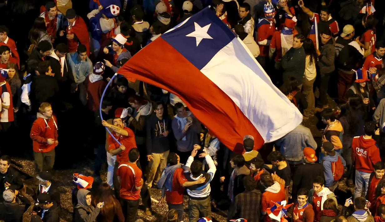 Suporter Chili mengibarkan bendera nasional Chili merayakan kemenangan Chili atas Argentina di final Copa Amerika 2015 di Santiago, (4/7/2015). Chili menang lewat adu penalti atas Argentina dengan skor 4-1. (REUTERS/Andres Stapff)