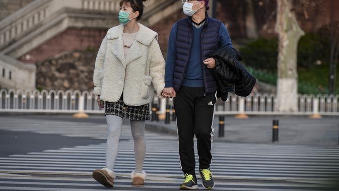 Warga Wuhan, Provinsi Hubei, berjalan-jalan di luar mengenakan masker. (dok. STR / AFP)