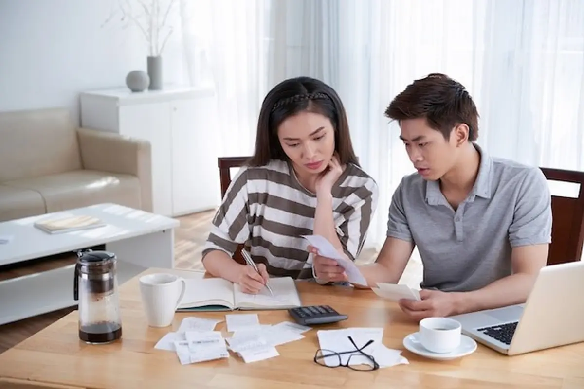 Pasangan Suami Istri Sedang Mencatat Pengeluaran di Buku