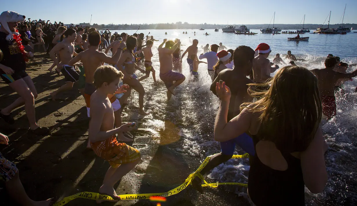 Orang-orang berlari menuju pantai untuk ambil bagian dari acara tahunan Polar Bear Swim di Vancouver, Kanada (2/1/2016). Meski suhu di pantai tersebut mencapai 3 derajat celcius, mereka tetap antusias. (REUTERS / Ben Nelms)